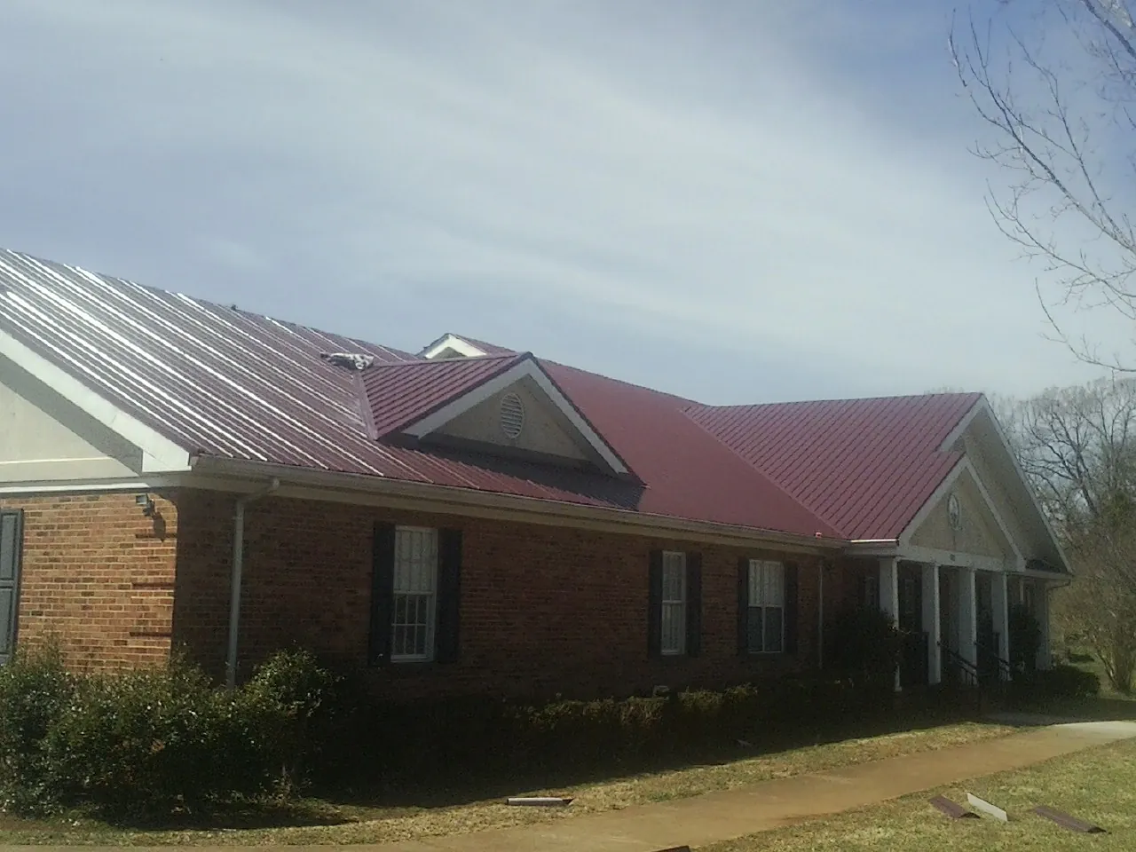 Red metal roof with gabled entries on a long brick building in Great Falls
