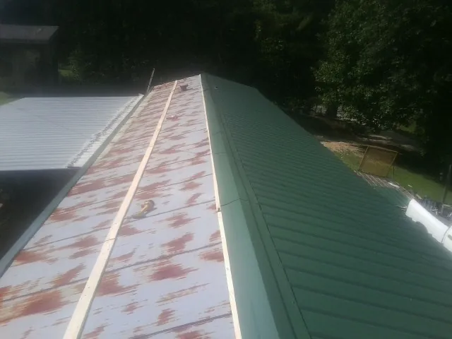 Old rusted panels beside newly installed green metal roofing — Wind Damage Roof Repair by Roofing Brothers in Great Falls