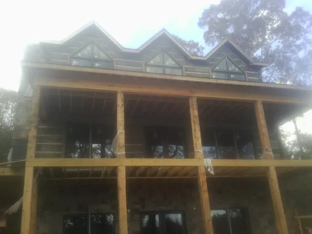 Dormers and porch framing on a large log home under construction — Roof Coating work by our crew in Great Falls