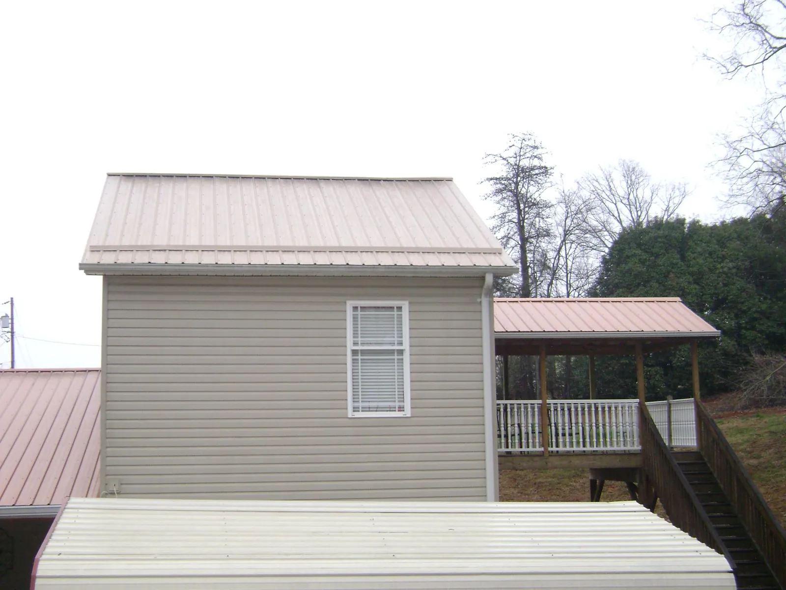 Tan metal roofs on a two story addition and attached porch, from a Roof Replacement job in Great Falls